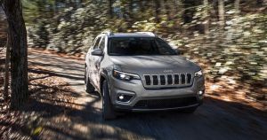 A silver 2019 Jeep Cherokee driving on a forest road near Sheboygan, WI