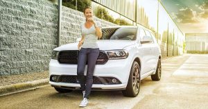A woman leaning on the hood of a 2020 Dodge Durango in Sheboygan, WI
