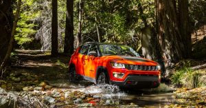 An orange 2020 Jeep Compass driving through a shallow creek near Sheboygan, WI
